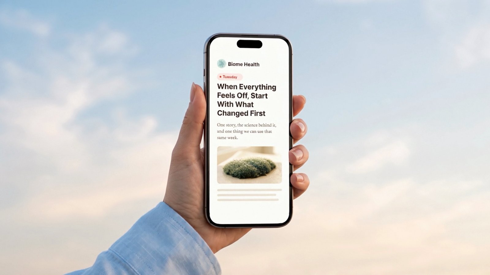 Hand holding a phone with a Biome Health article against the sky