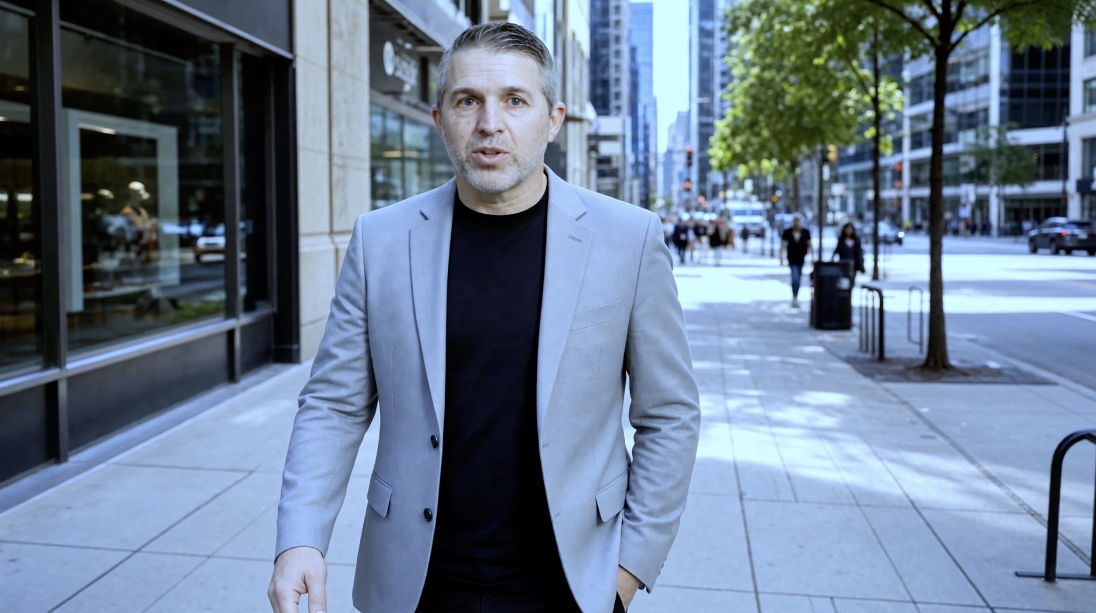 Shane Mara walking past a small business storefront delivering the opening line