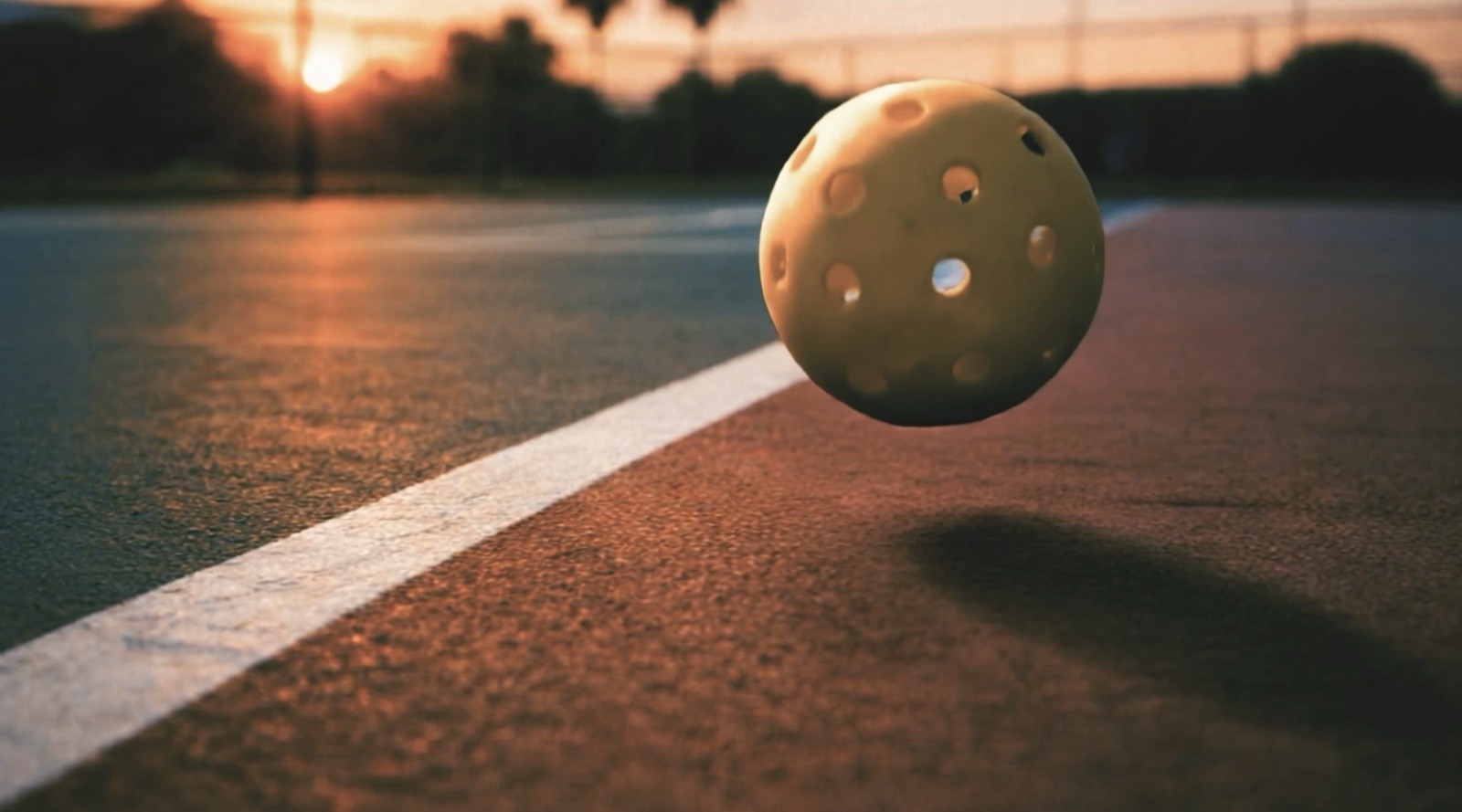 AI-generated cinematic shot of a pickleball mid-bounce on a sunlit court at dusk